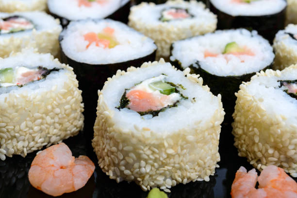 istock Traditional eastern dish with salmon sushi rolls on a black plate. 645218236