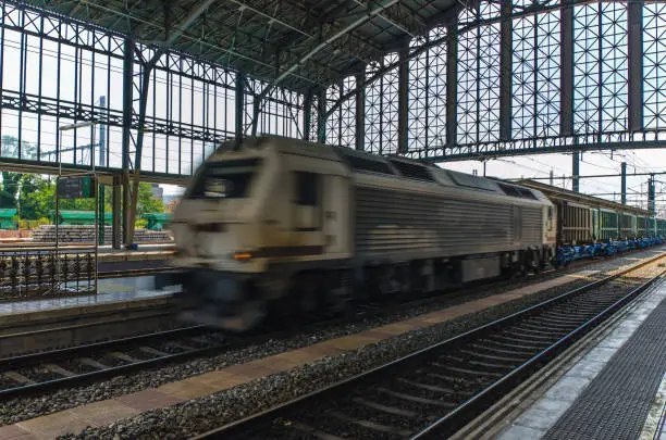 A freight train or goods train in motion on a train station. Motion blur