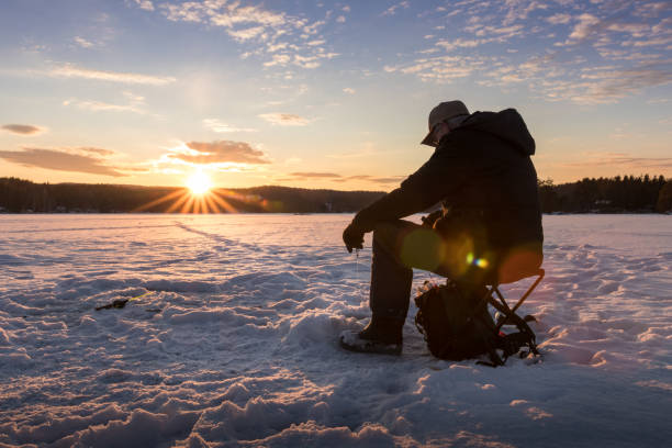 подледная рыбалка на озере в норвегии на закате. - ice fishing стоковые фото и изображения