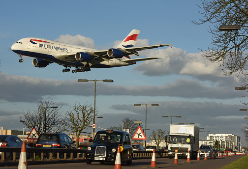British airways airbus 380 arrives into London Heathrow airport (from Beijing) passing over the perimeter road traffic as it lands