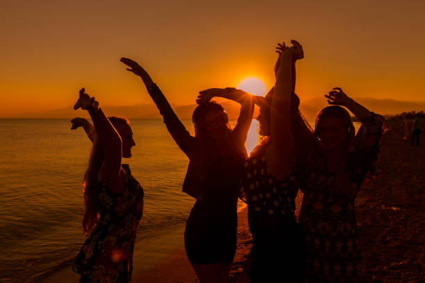 jóvenes amigos bailando en la playa al atardecer - beach party friendship teenage girls fotografías e imágenes de stock