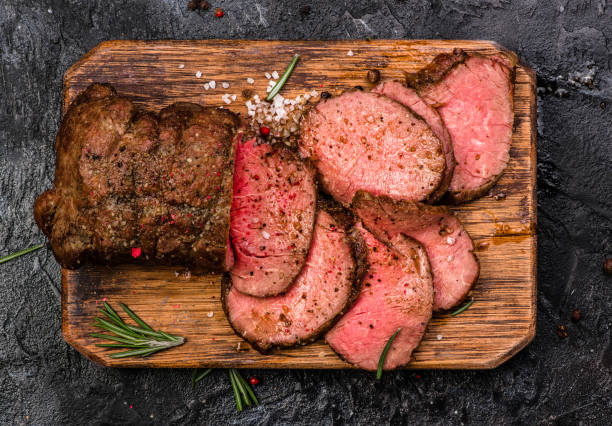 roast beef en tabla de cortar con sal y pimienta. vista superior. - roast beef fotos fotografías e imágenes de stock