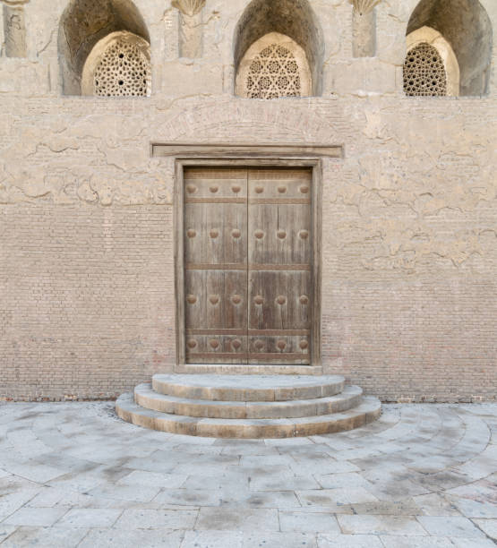 istock Wooden aged vaulted door and threee ornate engraved vaulted windows 645257678