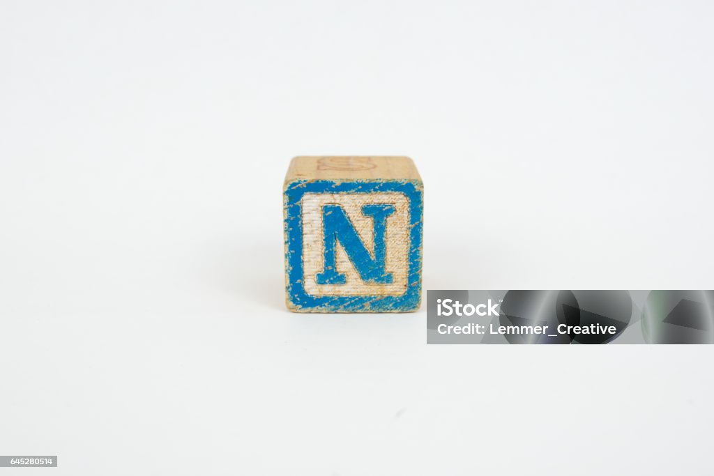 The Letter N in Colorful Wooden Childrenâs Blocks Letter N on a blue wooden childrenâs alphabet block. Isolated on a white background. Educational, Creative, Playful and Learning Concept. The blocks are intentionally worn, giving a more authentic or played with look. Alphabet Stock Photo