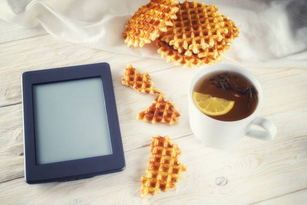 Cup of tea, waffle and ebook closeup. Copyspace