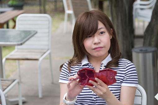 Young college student thinking and looking away, while holding her smartphone.