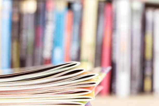 edge of colorful magazine stacking with  blurry bookshelf stock photo