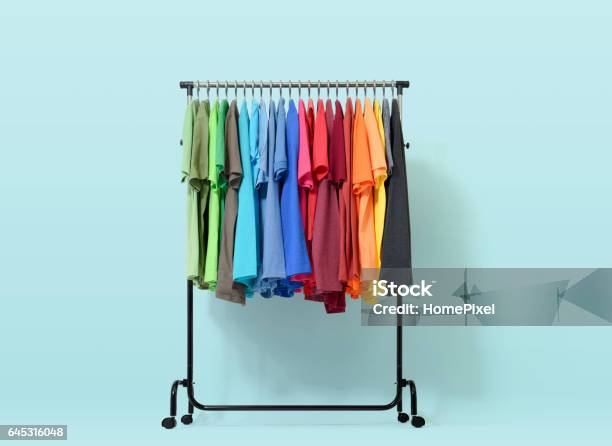 Estante Móvil Con Ropa De Color Sobre Fondo Azul Claro Foto de stock y más banco de imágenes de Vestimenta