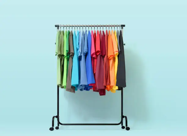 Mobile rack with color clothes on light blue background. File contains a path to isolation.