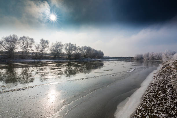 Beautiful winter scenery with trees covered by frost, along frozen river