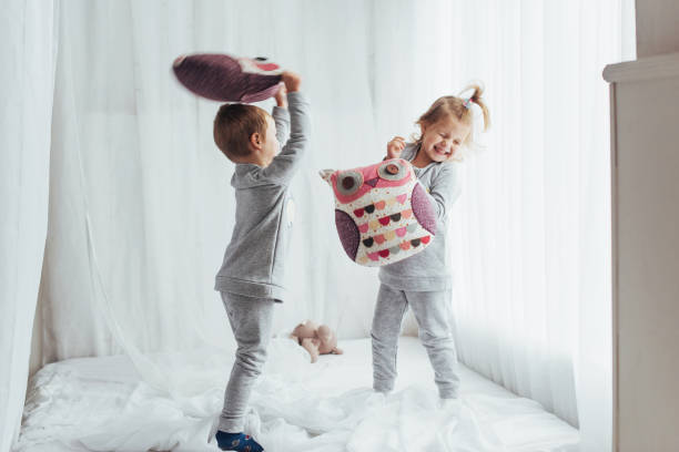 Children in pajamas Children in soft warm pajamas playing in bed floor length stock pictures, royalty-free photos & images