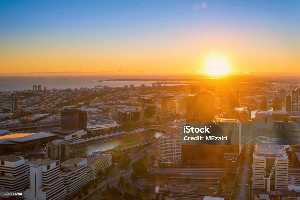 Melbourne city skyline An aerial view of Melbourne cityscape including Yarra River and Victoria Harbour in the distance during sunset with beautiful sun ray bursting through clouds. Aerial View Stock Photo