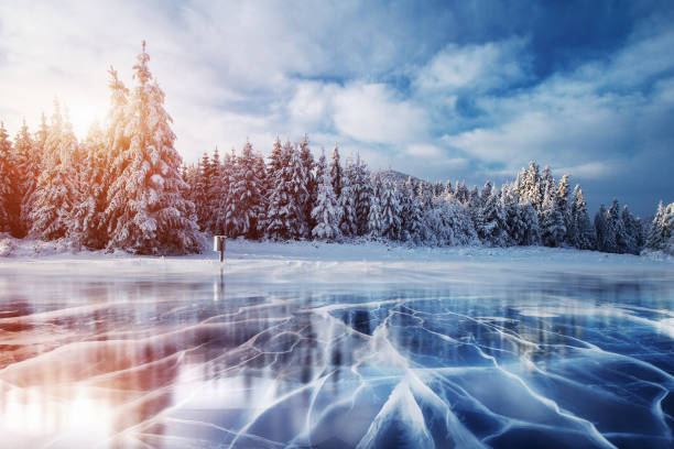 Blue ice and cracks on the surface of the . Blue ice and cracks on the surface of the ice. Frozen lake under a blue sky in the winter. The hills of pines. Winter. Carpathian Ukraine Europe winter sunrise mountain snow stock pictures, royalty-free photos & images