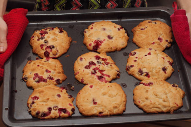 Woman holding oven tray with cookies.