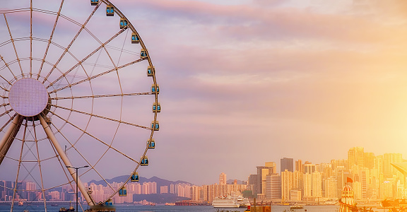 The popular icon Observation Wheel in Hong Kong island at sunset near Ferry Pier arera with landmark buildings in background.