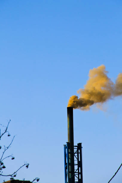 istock Dark smoke from a chimney against blue sky 645373552