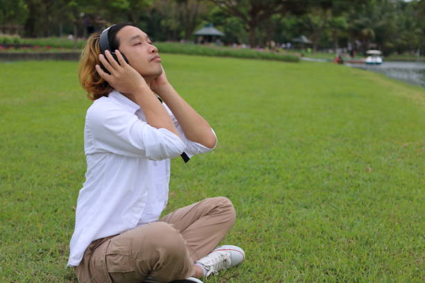 retrato de um jovem descansando com fones de ouvido - lying on side audio - fotografias e filmes do acervo