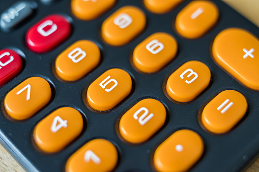 Keyboard of old pocket calculator. Orange and red keys on black background.