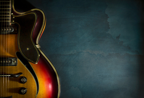 Close-up of old electric jazz guitar on a dark blue background with copy space