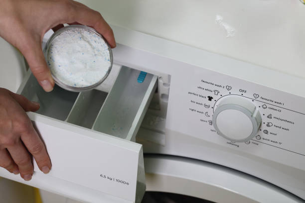 istock Close up on women hand puting laundry detergent into the washing machine 645415482