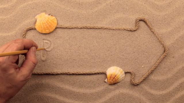 BEACH inscription written by hand on the sand, in the pointer made from rope