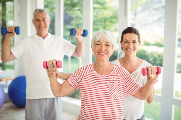 istock Female trainer assisting senior couple in performing exercise 645421992