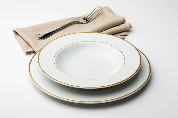 istock Empty round white plate and bowl with napkin and fork 645423592