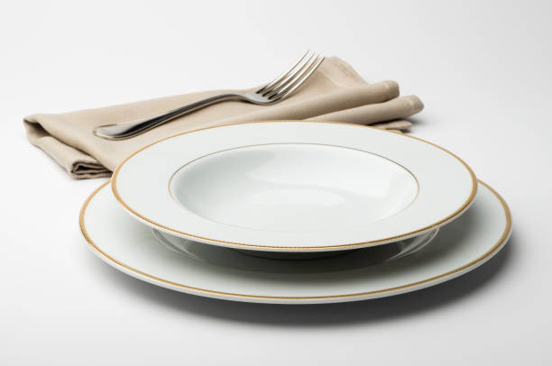 istock Empty round white plate and bowl with napkin and fork 645425834