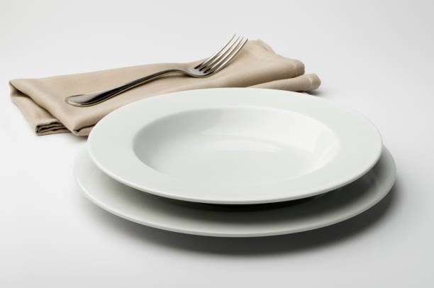 istock Empty round white plate and bowl with napkin and fork 645426208