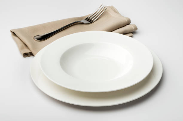 istock Empty round white plate and bowl with napkin and fork 645426532