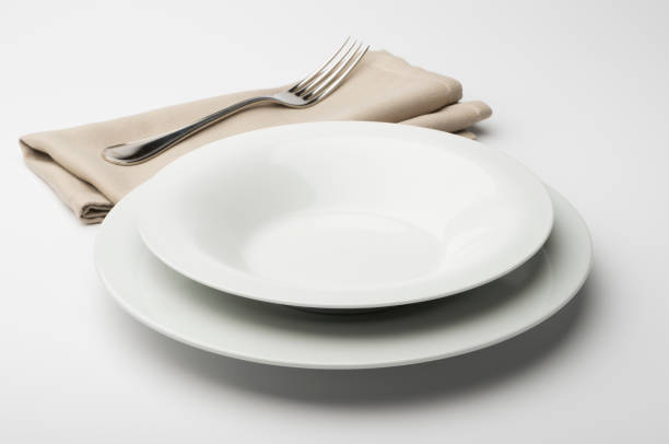 istock Empty round white plate and bowl with napkin and fork 645429388