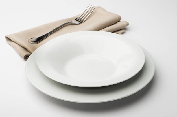 istock Empty round white plate and bowl with napkin and fork 645430832