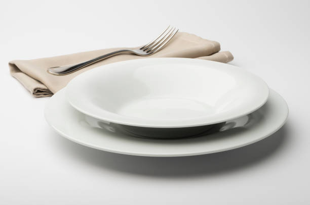 istock Empty round white plate and bowl with napkin and fork 645431924