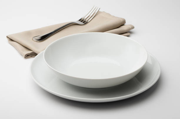 istock Empty round white plate and bowl with napkin and fork 645432404