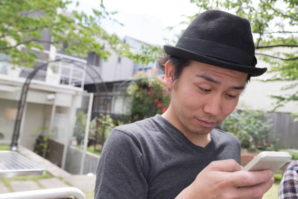 A confused japanese student gazing at his smart phone.