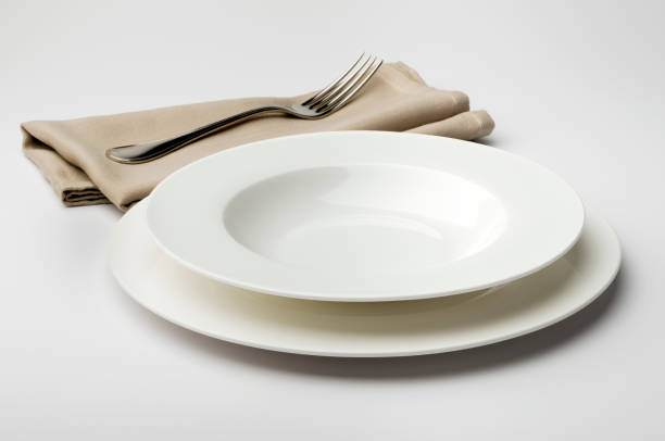 istock Empty round white plate and bowl with napkin and fork 645435598