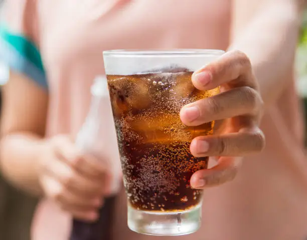 Woman hand giving glass of cola.Glass of cola ,Soft drinks with ice.