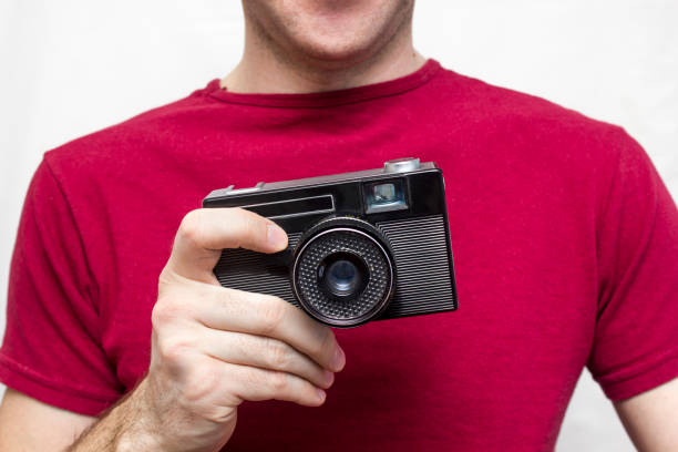 istock Man in a red t-shirt with old camera 645446124