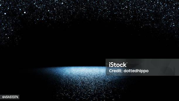 Twinkling Blue Glitter Falling On A Flat Surface Lit By A Bright Spotlight Stock Photo - Download Image Now