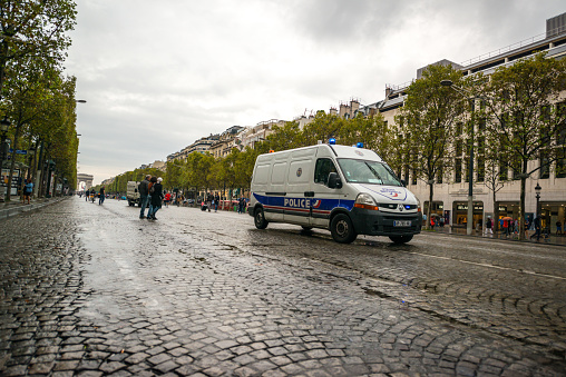 Paris, France - September 25, 2016: Car Free Day in Paris. Champs-Elysees Quartier and many neighbor streets closed for all traffic and open for pedestrians and cyclists. Police car moving on Avenue des Champs-Elysees. People walking under light rain.
