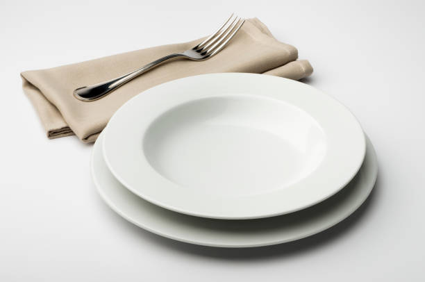 istock Empty round white plate and bowl with napkin and fork 645455378