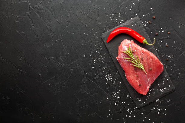 istock raw beef steak with rosemary and peppers on dark stone 645477542
