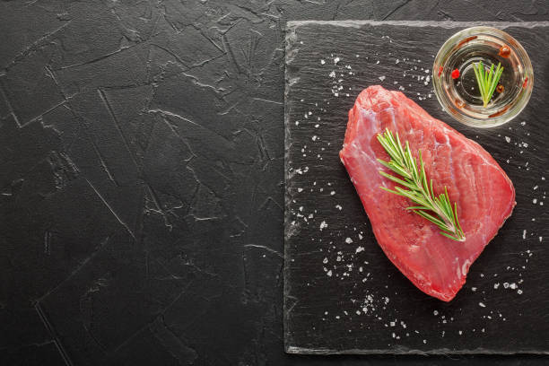 istock raw beef steak with rosemary and peppers on dark stone 645477584