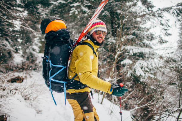 Young man with ski standing in the snow forest stock photo