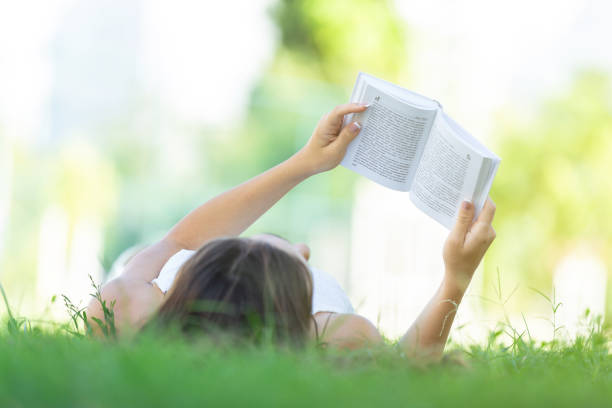 istock Woman reading book on grass 645487394