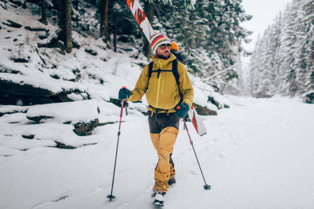 Young man with ski walking in the snow forest stock photo