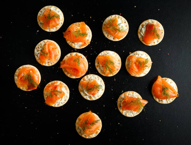 Smoked Salmon and soft chees canapes appetizers with chives on black table Smoked Salmon and soft chees canapes appetizers with chives on black table. blini photos stock pictures, royalty-free photos & images