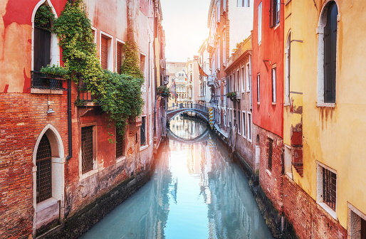 Traditional Gondolas on narrow canal between colorful historic houses in Venice Italy