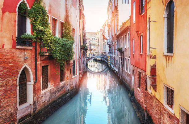 Traditional Gondolas on narrow canal between colorful historic houses in Venice Italy stock photo