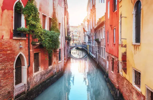 Traditional Gondolas on narrow canal between colorful historic houses in Venice, Italy